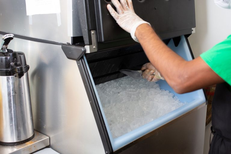 A view of an employee scooping ice out of an ice machine, in a restaurant setting, Scotsman Vs Hoshizaki Ice Machines What Are The Differences