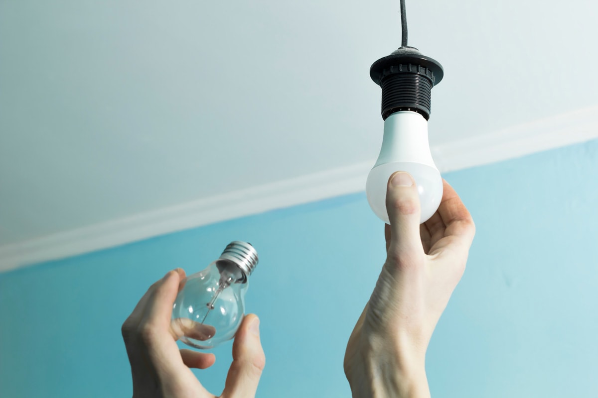 Incandescent lamp is changed to LED light by the hands of a man.