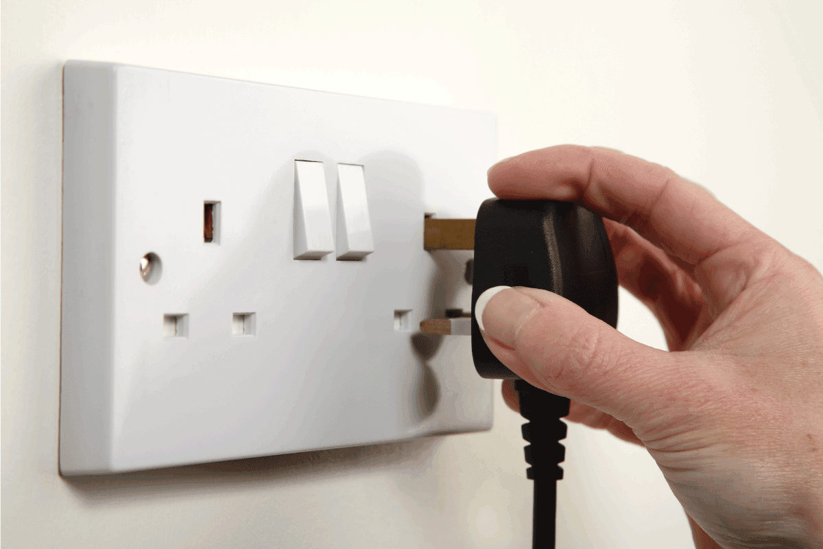 man plugging in power cable to a properly grounded wall outlet