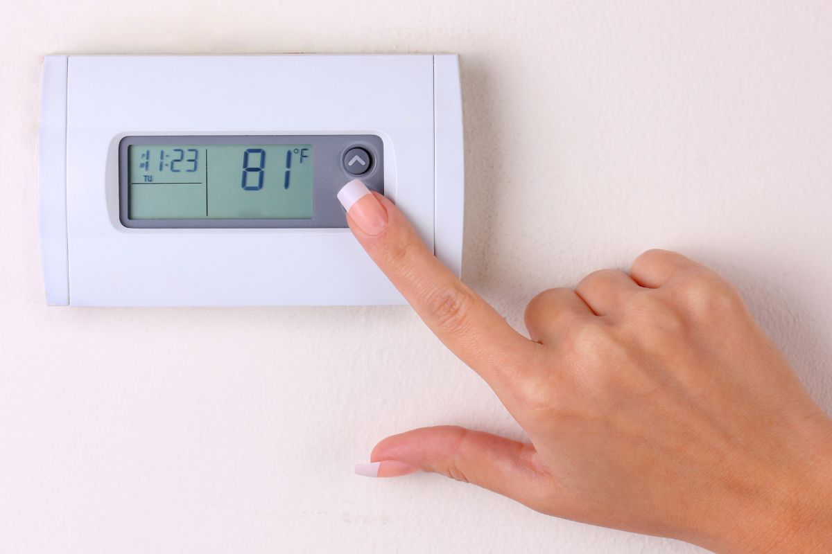 thermostat. woman's hand setting the room temperature on a modern programmable wall heater.