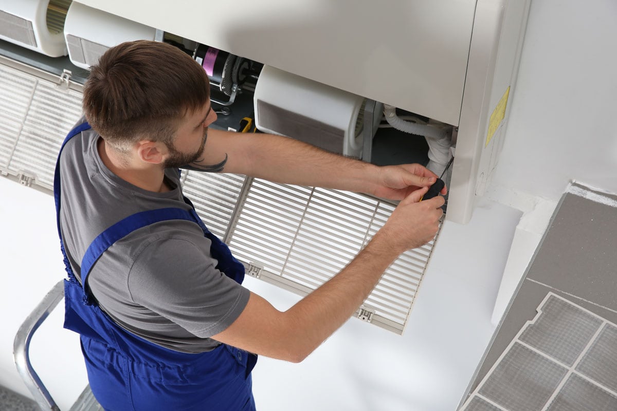 young male technician repairing air conditioner