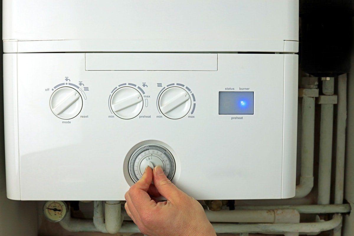 A Hand Adjusting A Dial On A Home Combi Boiler.