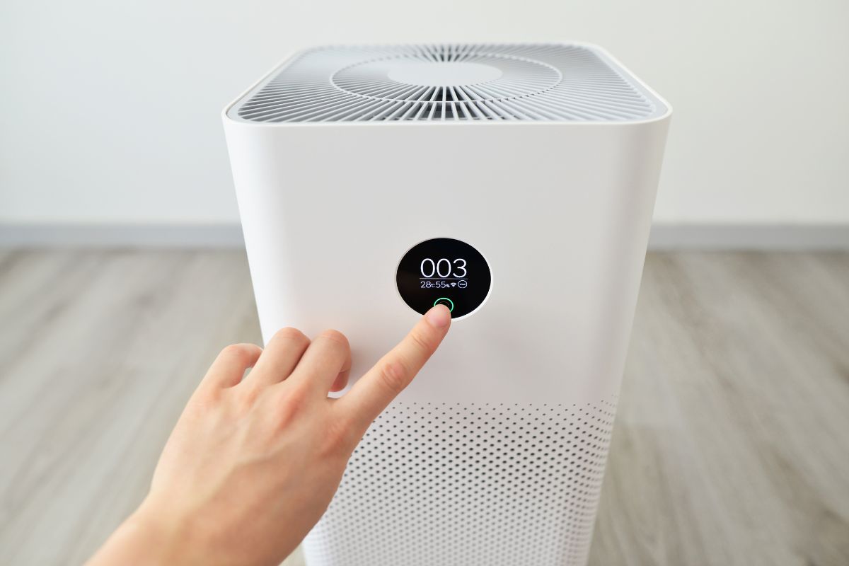 Close up of male hand pressing button on air purifier Indoor air purifier with digital monitor screen in bedroom, that show air quality in the room and air pollution levels in the room. 