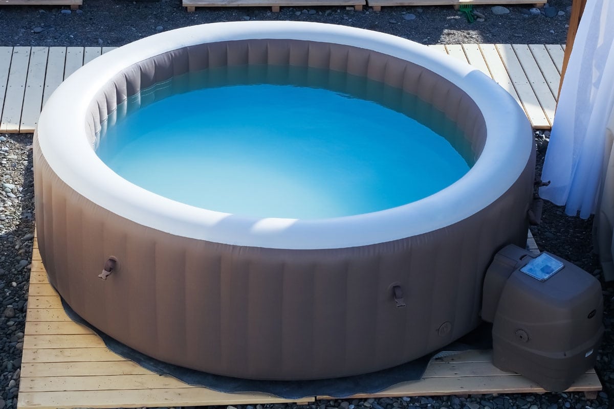 Inflatable brown and white swimming pool with turquoise water outdoors in the summer sun at the beach recreation area