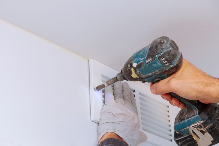 Man is holding hand drill in hands. Worker installing the wall bathroom vent restoration process repair works renovation in the flat., Can An Exhaust Fan Be Installed Over A Shower?