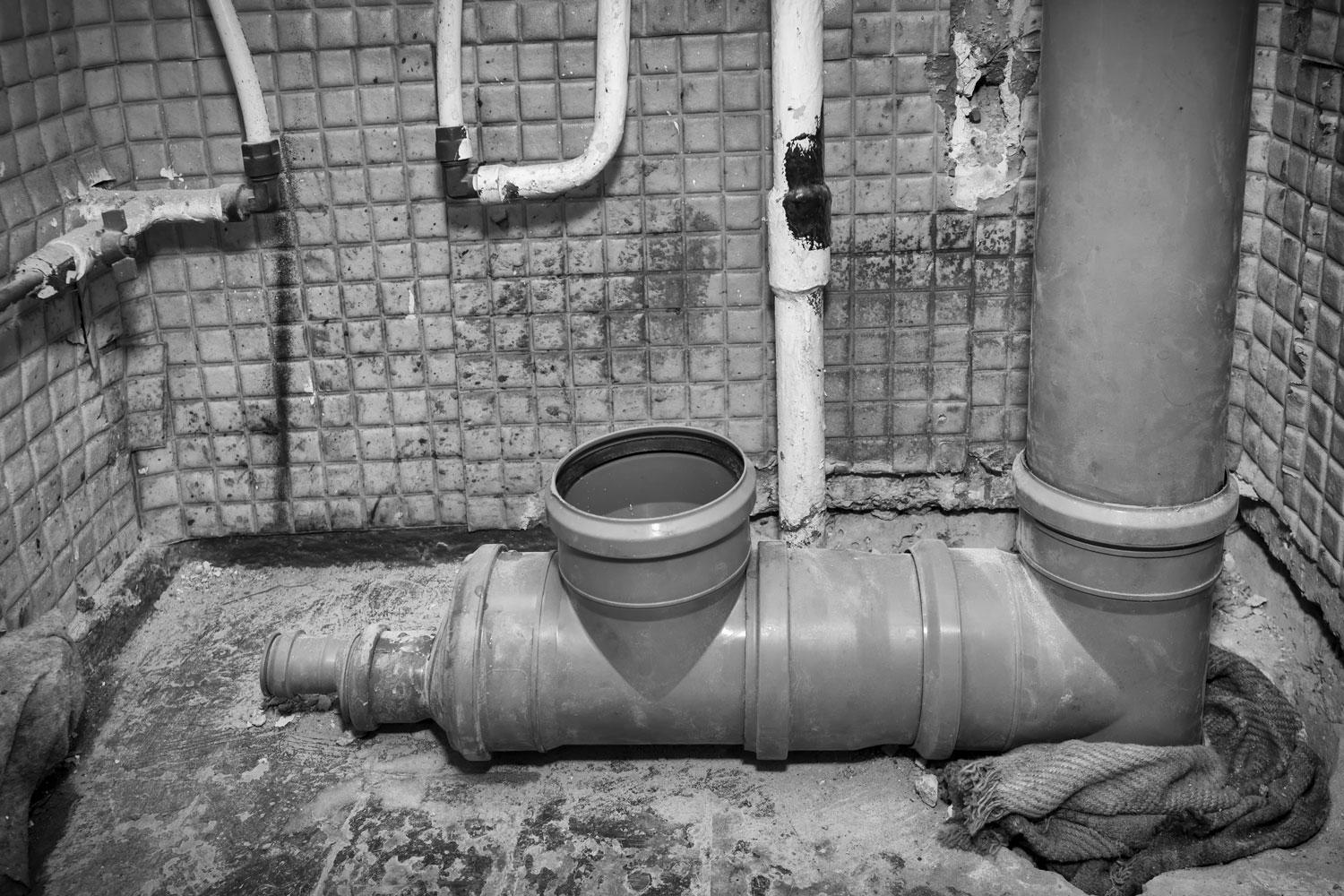 Toilet apartment in a multi-storey residential building in the city. Replacing an old iron sewer pipe with a new plastic one. Installation of the system. Black and white photography 