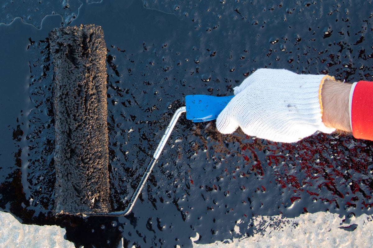 waterproofing coating worker applies bitumen mastic