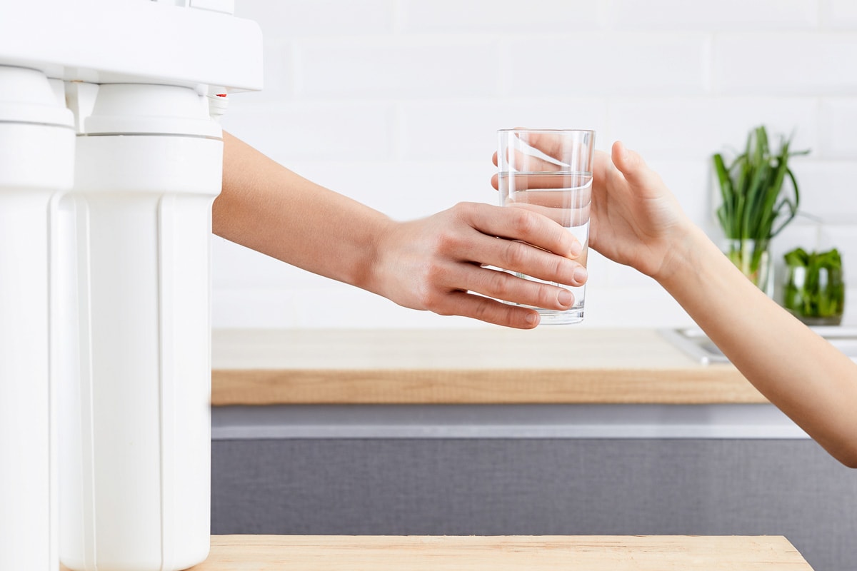 woman's hand gives a glass of purified water to her child