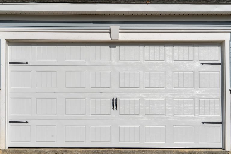 Double car classic insulated steel raised panel garage door framed with a white trim to add accent, on a new American home, How To Install US Energy Garage Door Insulation?