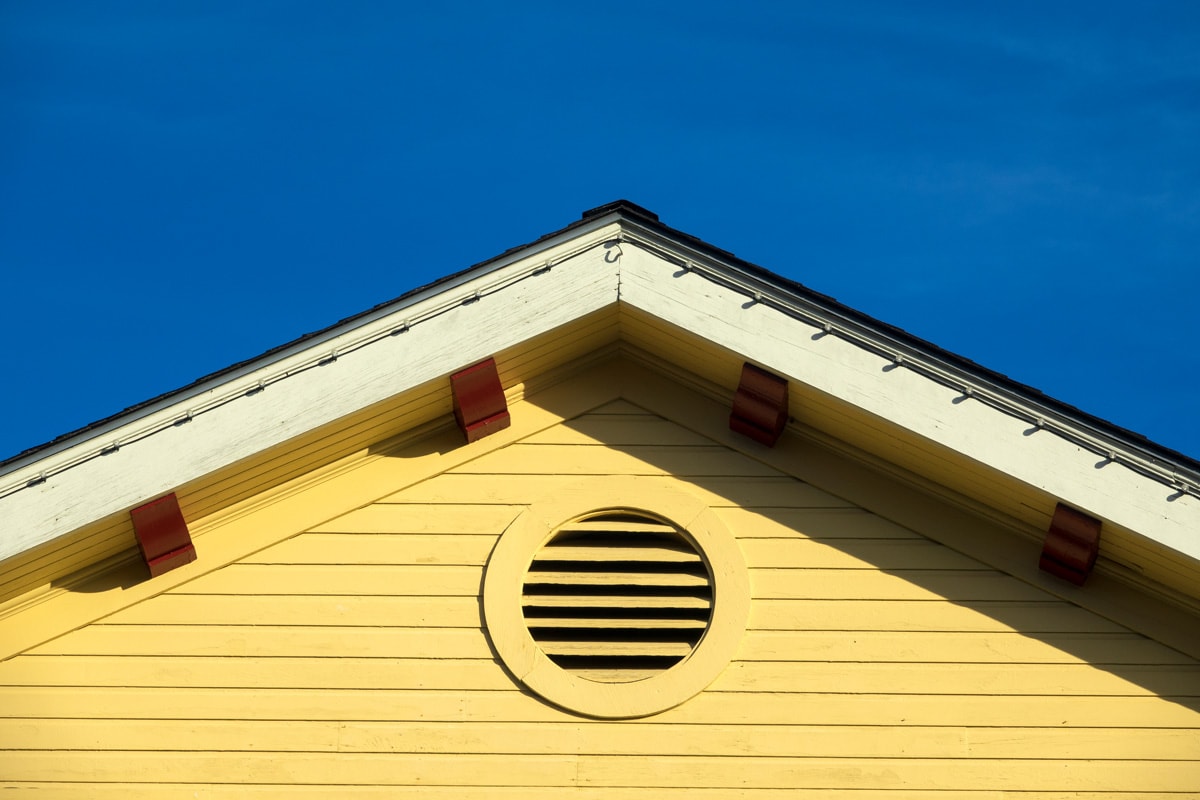 A gable vent in a yellow wall