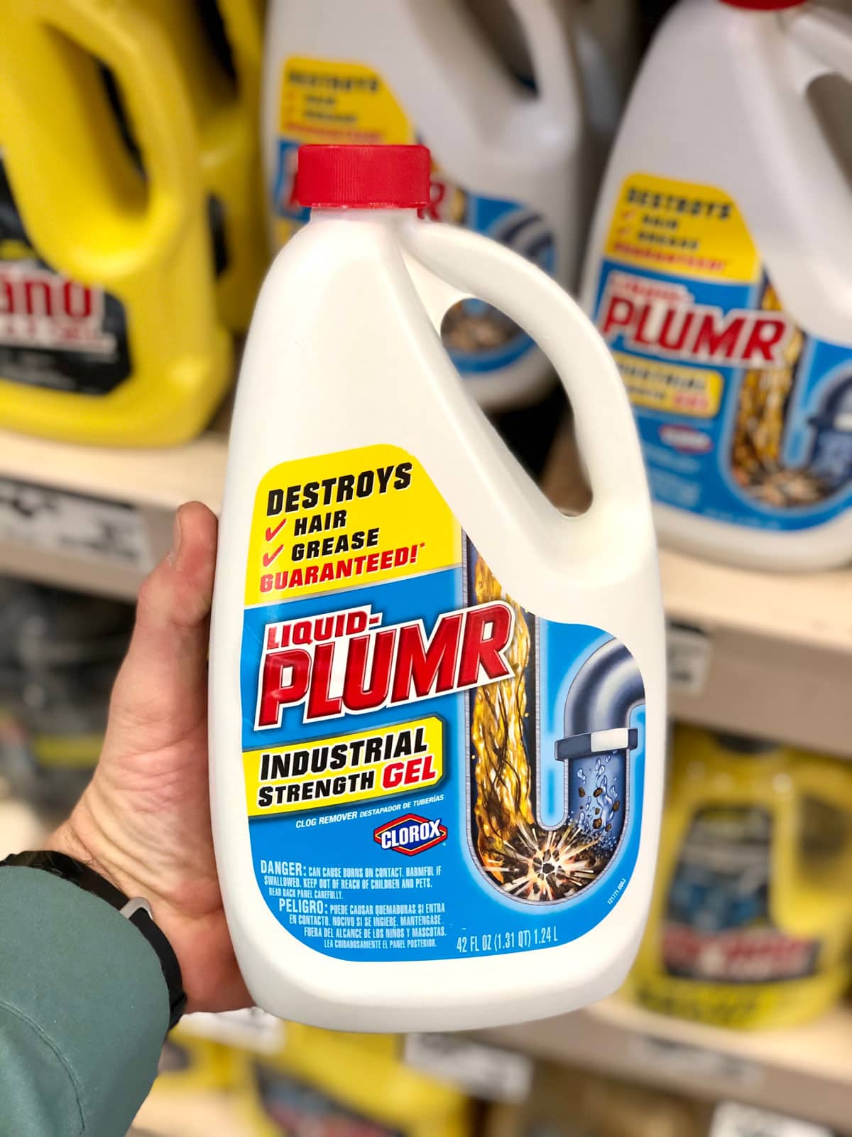 Man holding up a bottle of Liquid Plumr branded Industrial Strength Drain Clearing Gel.