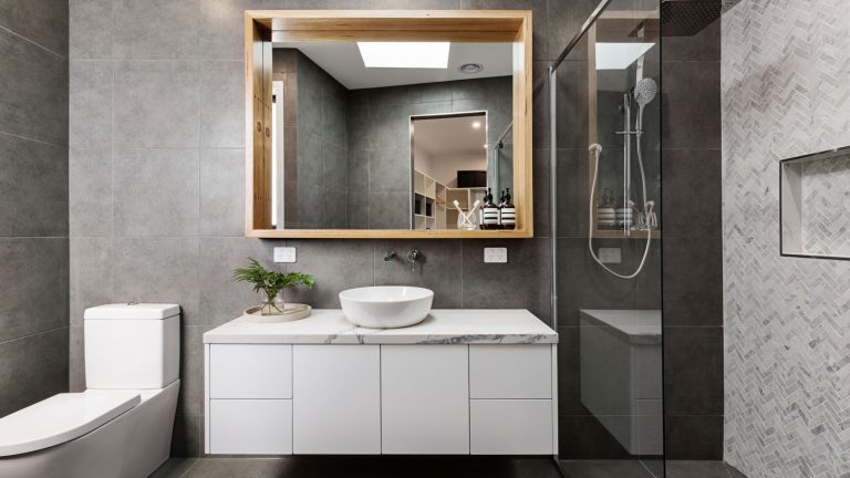 Interior of an ultra modern bathroom with white vanity and and gray stucco finished walls