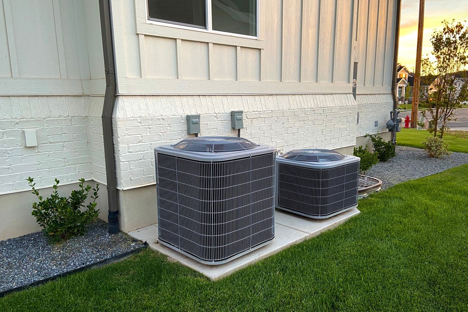 Two different sizes of air conditioning units mounted on a concrete pad 