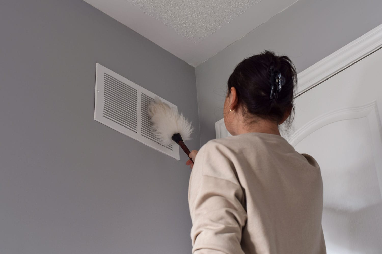 Woman cleaning the air vent of the house